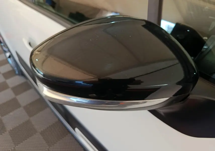 Gros plan sur le rétroviseur noir brillant côté conducteur d'une Citroën C3 blanche vue de profil gauche.