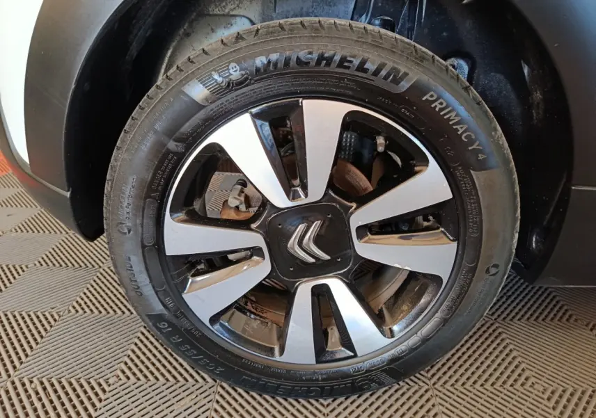 Gros plan sur la roue avant gauche d'une Citroën C3 blanche, mettant en valeur la jante alliage bicolore et le pneu Michelin.