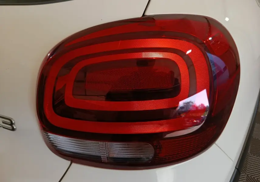 Gros plan sur le feu arrière droit rouge et blanc d'une Citroën C3 blanche, version Shine Business 2021.