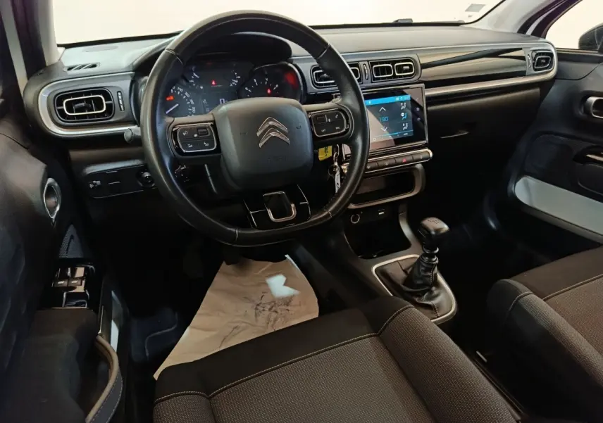 Vue intérieure côté conducteur de la Citroën C3 blanche 2021, volant cuir, écran tactile et boîte manuelle visible.