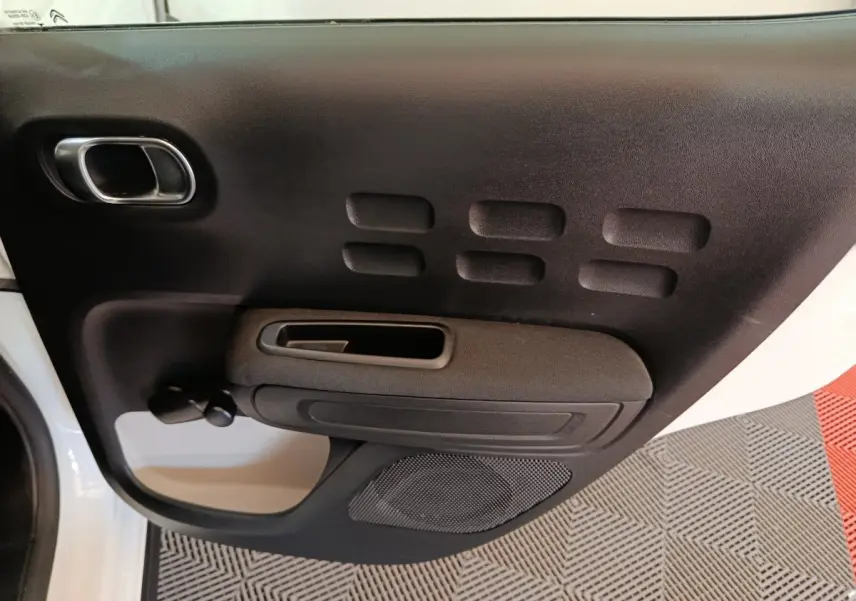 Vue rapprochée de la porte avant gauche noire et blanche de la Citroën C3 avec poignée intégrée et haut-parleur.