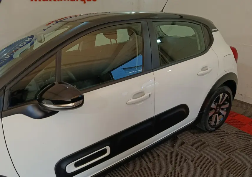 Vue latérale droite d'une Citroën C3 blanche avec protections noires sur les portes et rétroviseur noir brillant.