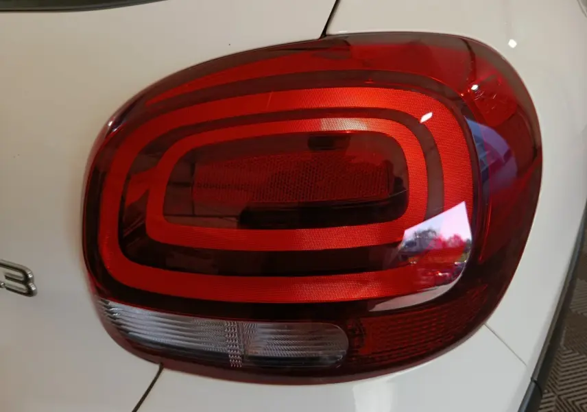 Gros plan sur le feu arrière droit rouge et blanc d'une Citroën C3 blanche, version 2021 PureTech Shine Business.
