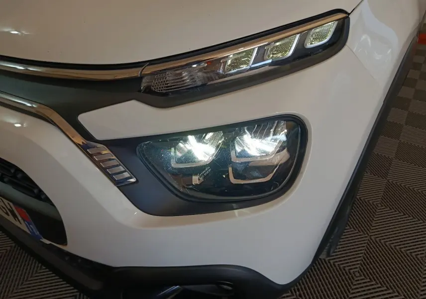 Gros plan sur le phare avant droit blanc d'une Citroën C3 2021 avec feux LED et détails chromés autour.