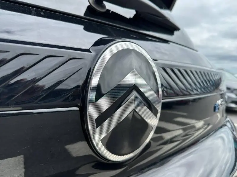 Gros plan sur l'emblème Citroën noir et argent à l'avant d'une C3 électrique 2025 en Noir Perla Nera.