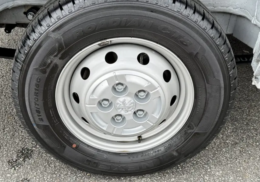 Gros plan sur la roue avant droite du Peugeot Boxer Fourgon blanc, mettant en valeur la jante acier et le pneu Nexen Roadian.