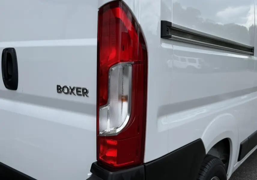 Gros plan sur l'arrière droit blanc du Peugeot Boxer Fourgon avec feu arrière rouge et logo BOXER visible.