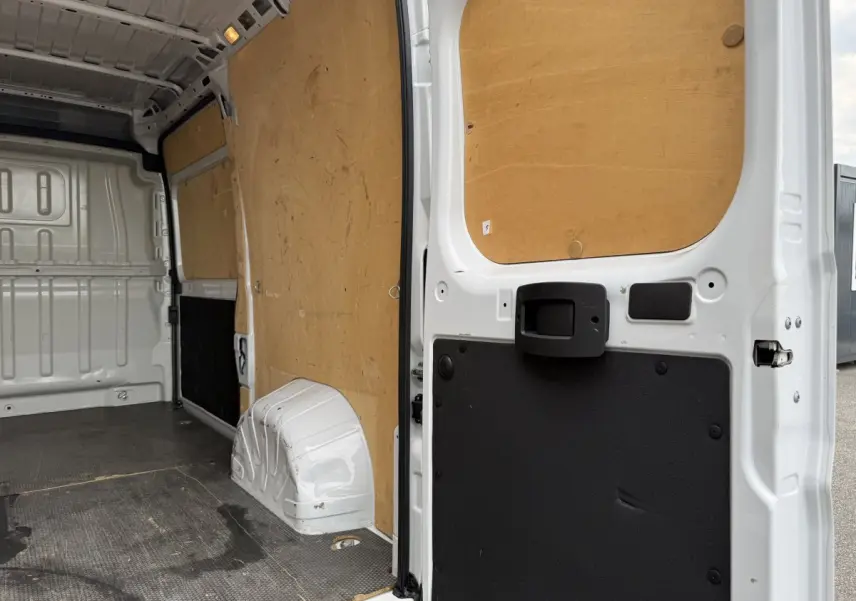 Vue intérieure arrière du Peugeot Boxer Fourgon blanc 2023, montrant la cloison pleine et le revêtement bois des parois.