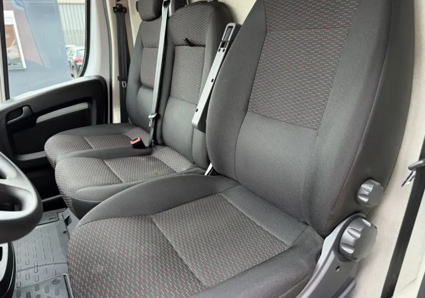 Vue intérieure rapprochée des sièges avant gris foncé à motifs rouges du Peugeot Boxer Fourgon 2023.