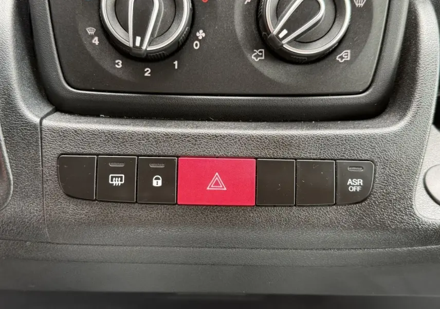 Gros plan sur la console centrale du Peugeot Boxer Fourgon blanc 2023, montrant les boutons de commande dont le bouton d'alerte rouge.