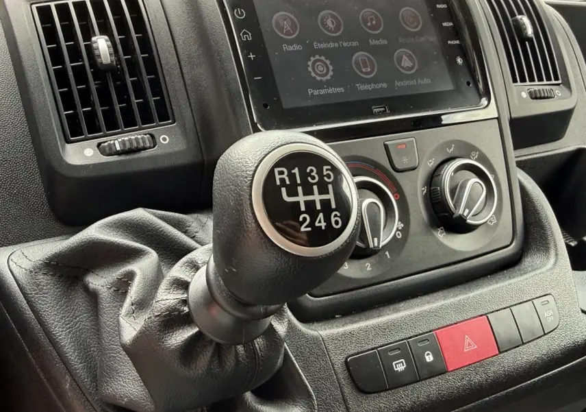 Gros plan sur levier de vitesse manuel et commandes de climatisation du tableau de bord du Peugeot Boxer Fourgon blanc 2023.