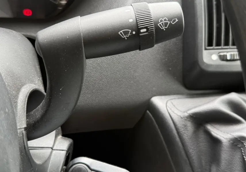Gros plan sur la manette d’essuie-glace et le levier de vitesse en cuir noir dans l’habitacle du Peugeot Boxer Fourgon blanc.