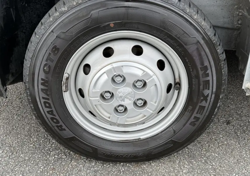 Gros plan sur la roue avant droite du Peugeot Boxer Fourgon blanc, avec jante acier et logo Peugeot central.