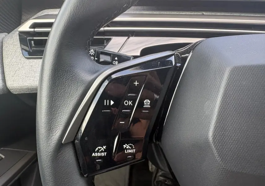 Gros plan sur les commandes au volant à gauche du Peugeot 3008 Hybrid noir, avec boutons de régulateur et assistance.