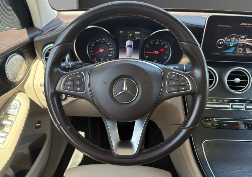 Vue intérieure centrée sur le volant cuir marron et tableau de bord beige du Mercedes GLC 350 E HYBRID FASCINATION 2017.