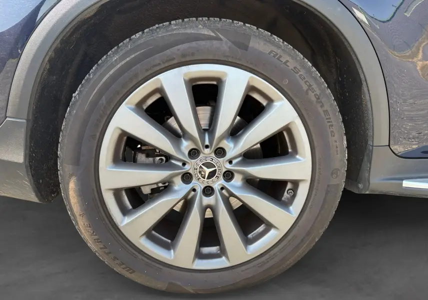Gros plan sur la jante alliage 19 pouces argentée du côté gauche d’un Mercedes GLC bleu 350 E Hybrid.