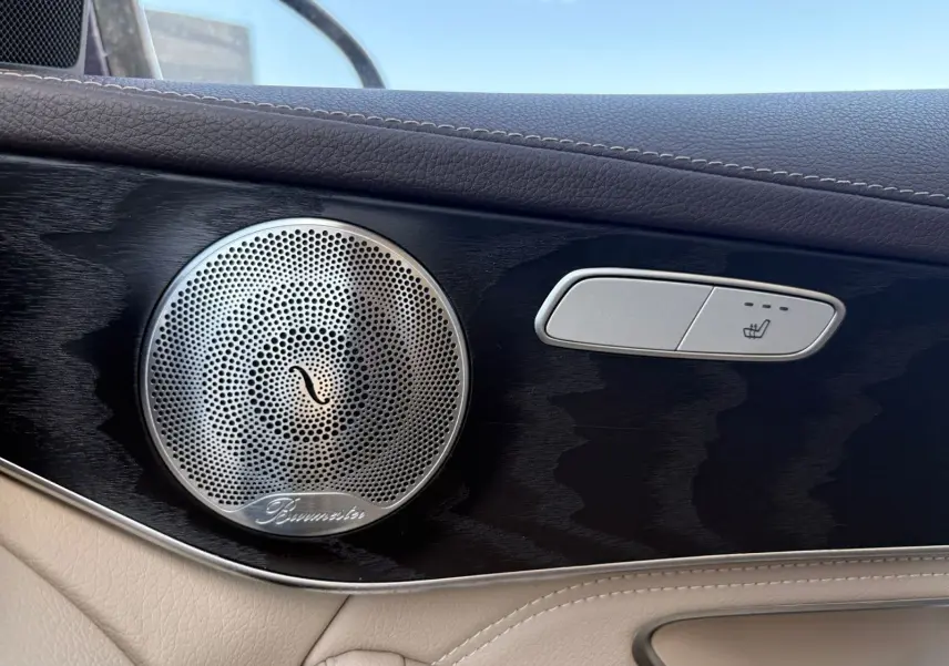 Gros plan sur la porte intérieure côté gauche d’une Mercedes GLC bleu, avec haut-parleur Burmester et bouton siège chauffant.