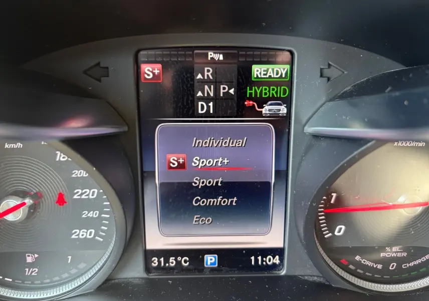 Tableau de bord de Mercedes GLC 350 E Hybrid bleu, affichage central mode Sport+ et indicateur hybride prêt.