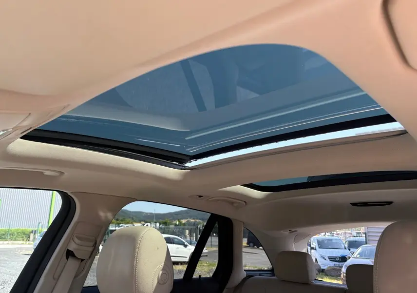 Vue intérieure du toit ouvrant panoramique ouvert sur Mercedes GLC 350 E Hybrid Fascination 4MATIC, sellerie cuir beige visible.