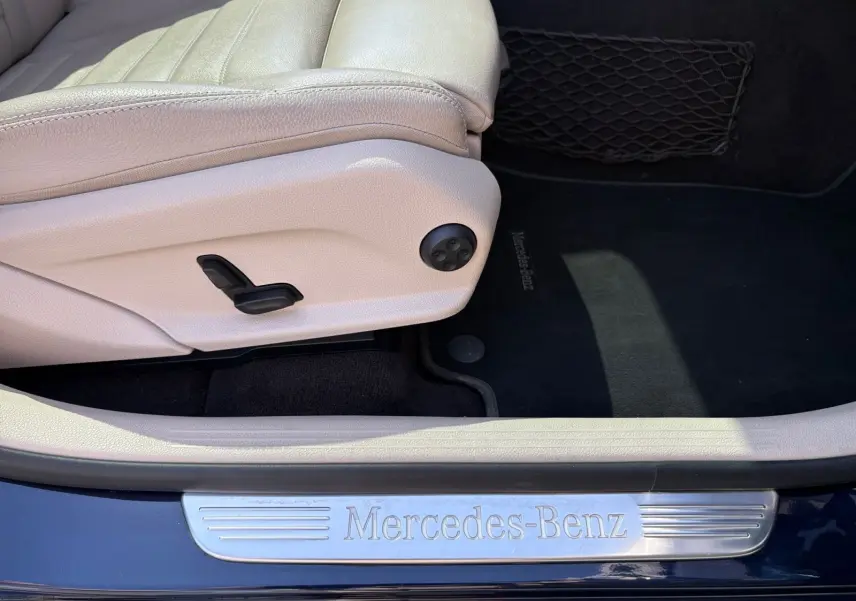 Vue rapprochée de la porte côté conducteur d’un Mercedes GLC bleu, avec seuil de porte Mercedes-Benz et siège cuir beige.