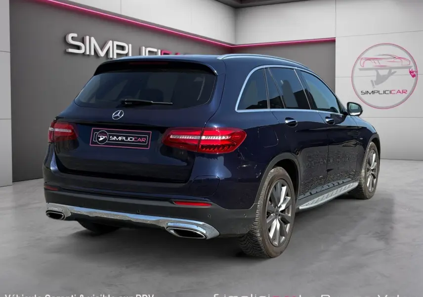Vue 3/4 arrière droite d'un Mercedes GLC 350 E Hybrid Fascination bleu avec jantes alliage et sorties d'échappement chromées.