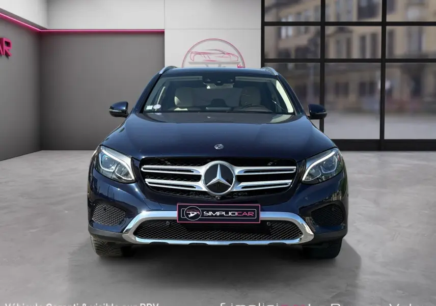 Vue avant d’un Mercedes GLC 350 E Hybrid Fascination bleu avec calandre chromée et phares LED allumés.