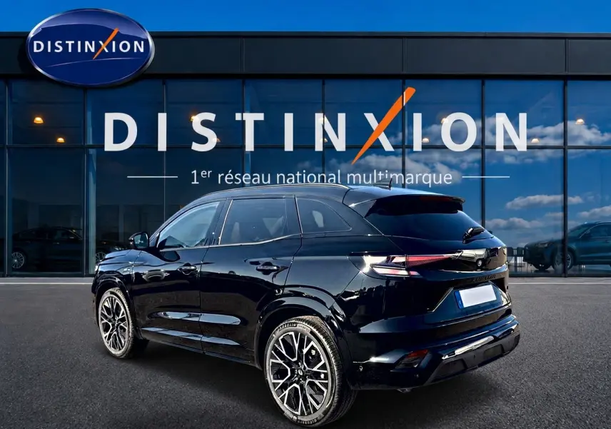 Renault Austral noir en 3/4 arrière droit, avec jantes alu et becquet arrière, devant une vitrine Distinxion.