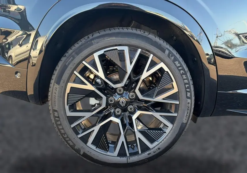 Gros plan sur la roue avant droite noire du Renault Austral 1.2 e-tech full hybrid avec jante alu bicolore design géométrique.