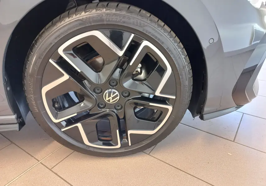 Gros plan sur la roue avant droite de la Volkswagen Golf 1.5 eTSI R-Line gris dauphin avec jante alliage noire et argent.