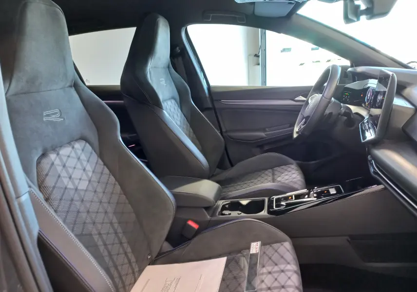 Vue intérieure côté gauche de la Volkswagen Golf 1.5 eTSI R-Line 2025 avec sièges sport noirs et tableau de bord moderne.