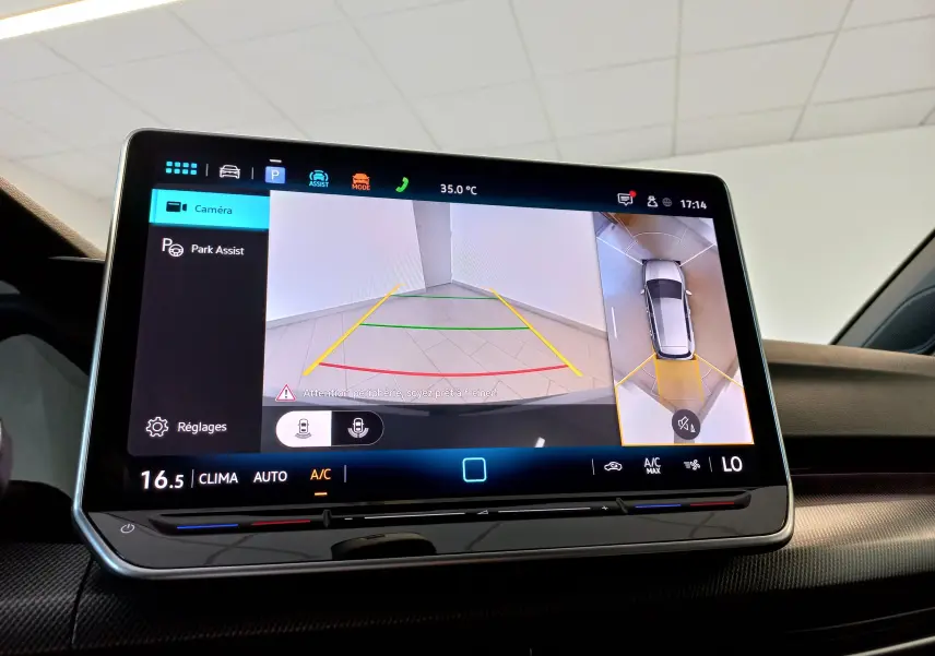 Écran tactile intérieur affichant la caméra 360° avec vue arrière et vue aérienne de la Volkswagen Golf gris dauphin.