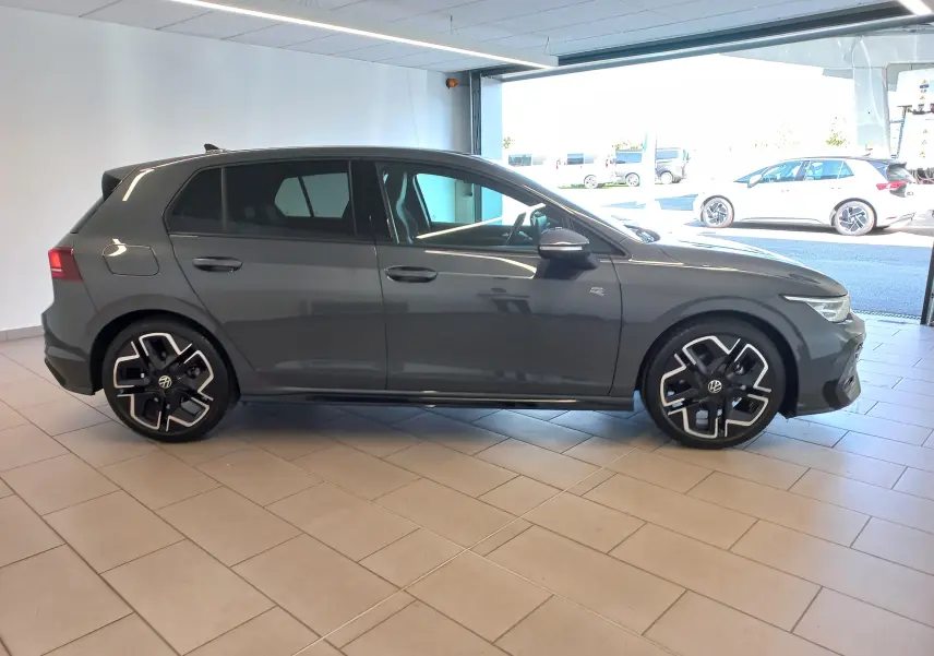 Vue de profil droit d'une Volkswagen Golf 1.5 eTSI 150 DSG7 R-Line Edition gris dauphin, avec jantes distinctives et vitres teintées.