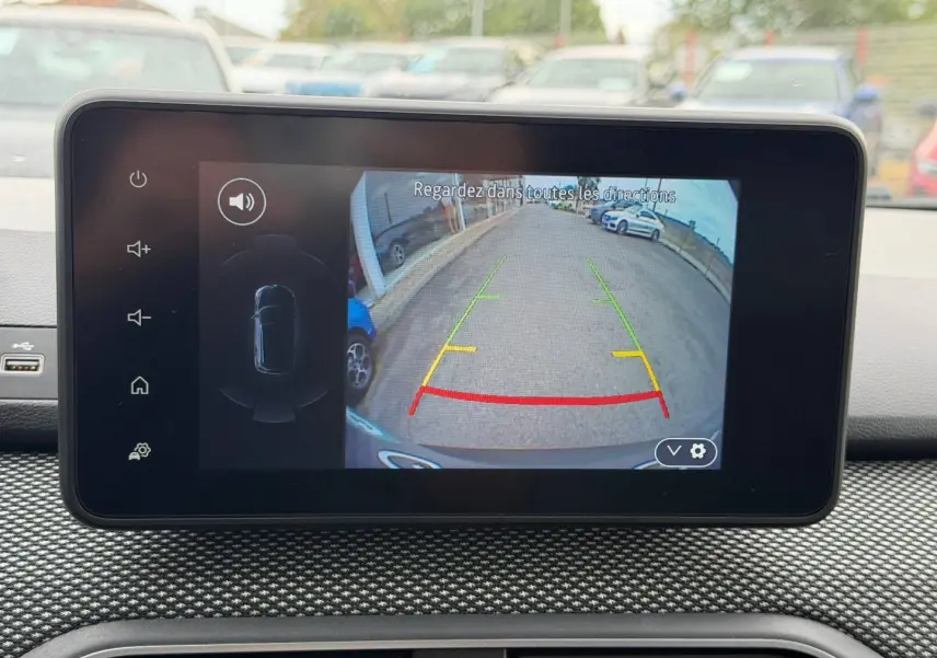 Écran tactile intérieur montrant la caméra de recul d'un Dacia Jogger vert Cèdre, vue arrière en stationnement.