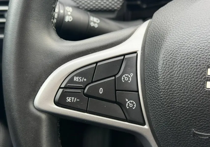 Gros plan sur les commandes de régulateur de vitesse sur le volant noir du Dacia Jogger 2025.