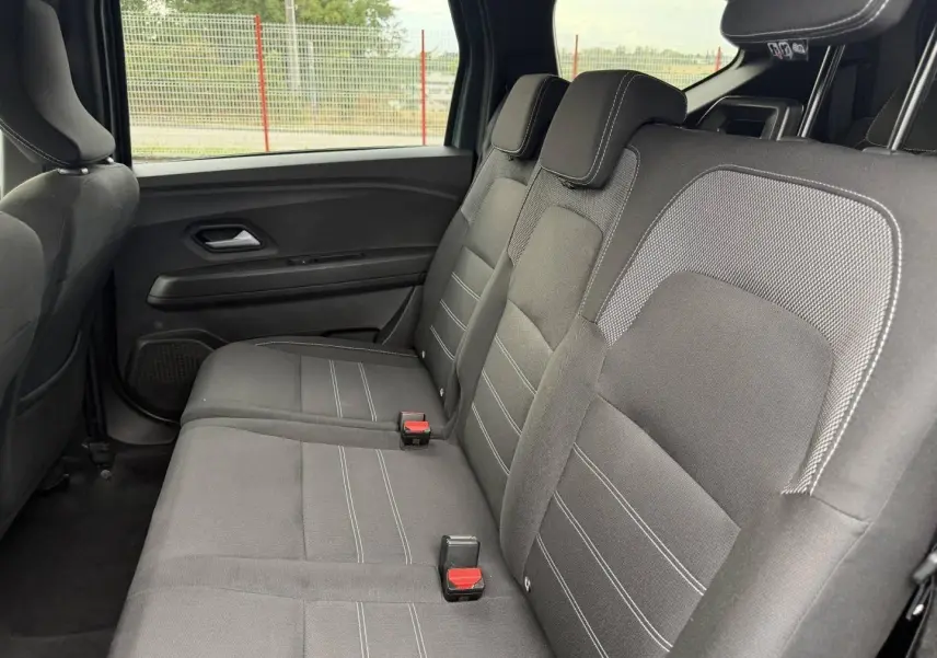 Vue latérale intérieure montrant la banquette arrière en tissu gris foncé du Dacia Jogger 2025.