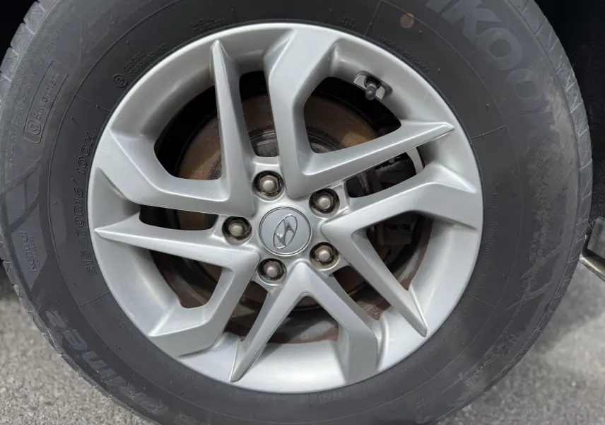 Gros plan sur la jante alliage argentée d'un Hyundai Tucson gris, mettant en valeur le logo Hyundai au centre.