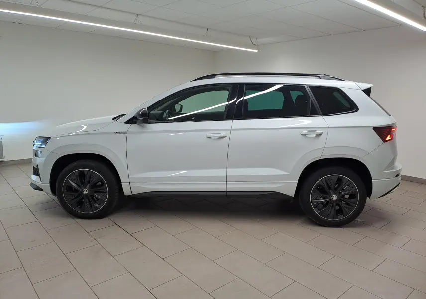 Vue de profil côté gauche d'un Skoda Karoq 2.0 TDI 116 DSG7 Sportline blanc lune avec jantes noires en intérieur.