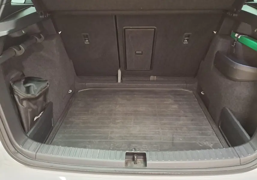 Coffre ouvert du Skoda Karoq blanc Lune 2022, vue intérieure montrant le tapis de sol et les rangements latéraux.