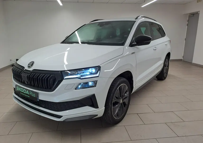 Vue 3/4 avant droite d’un Skoda Karoq blanc lune 2022 avec calandre noire et jantes alliage foncé Sportline.