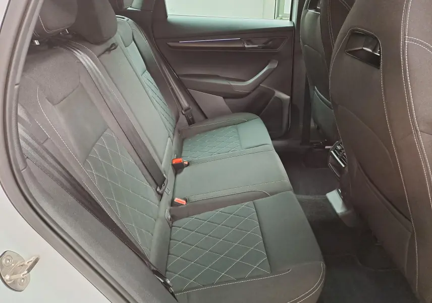 Vue intérieure côté gauche des sièges arrière en tissu noir avec surpiqûres blanches du Skoda Karoq 2022 Blanc Lune Sportline.