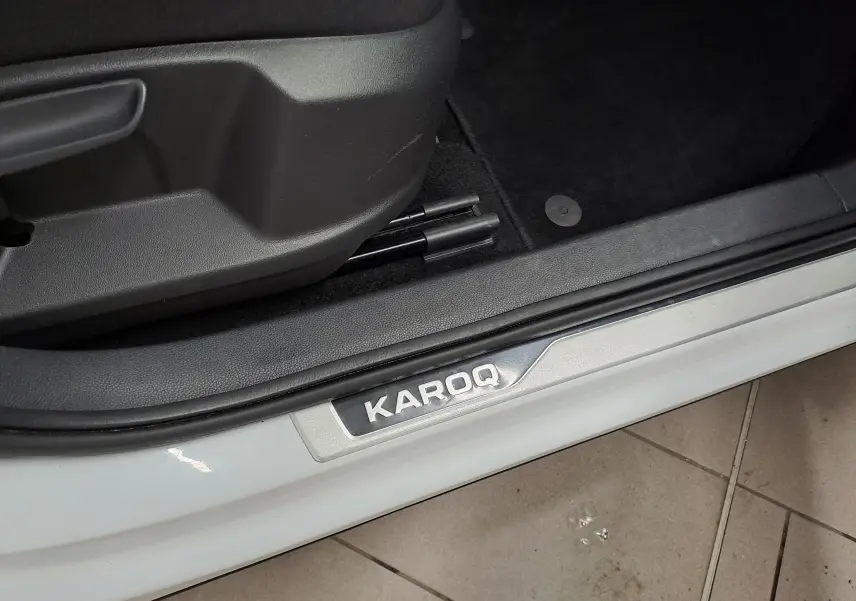 Gros plan sur la plaque de seuil de porte côté gauche du Skoda Karoq blanc lune, intérieur noir visible.