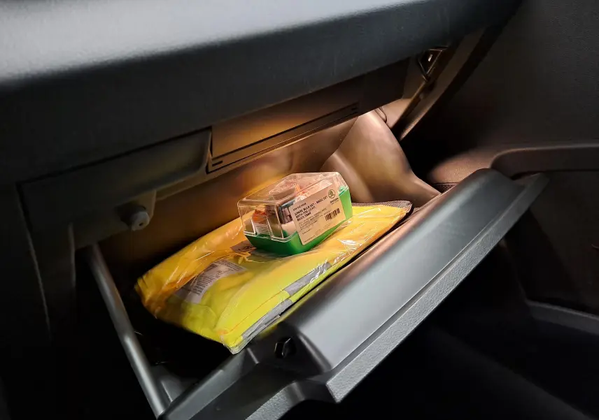 Gros plan sur la boîte à gants ouverte du Skoda Karoq 2.0 TDI 116 DSG7 Sportline 2022 avec gilet jaune et kit de sécurité.