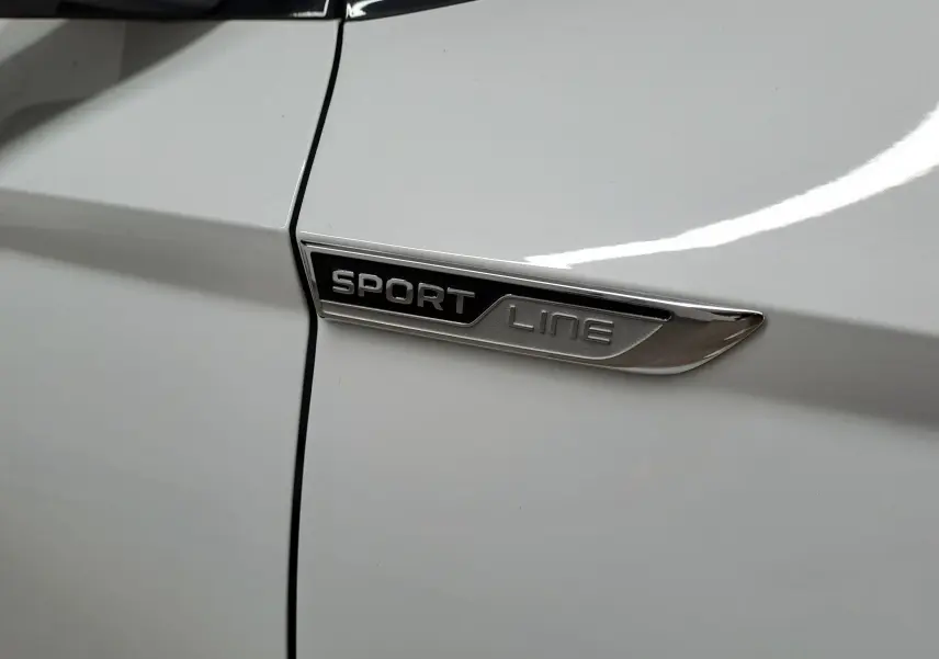 Gros plan sur l’inscription Sportline sur la portière blanche métallisée d’un Skoda Karoq 2022.