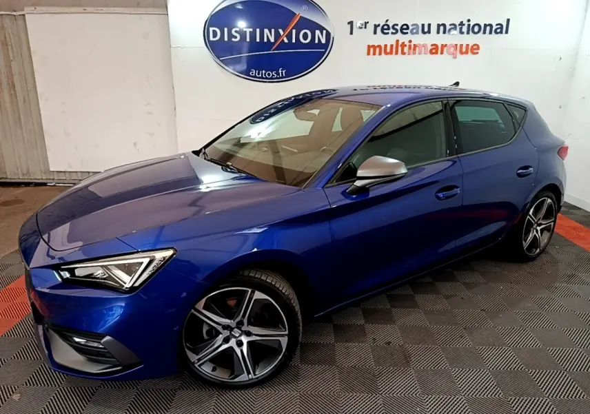 SEAT Leon 1.5 eTSI bleu en vue 3/4 avant droit, avec jantes alliage et rétroviseurs argentés dans un showroom.