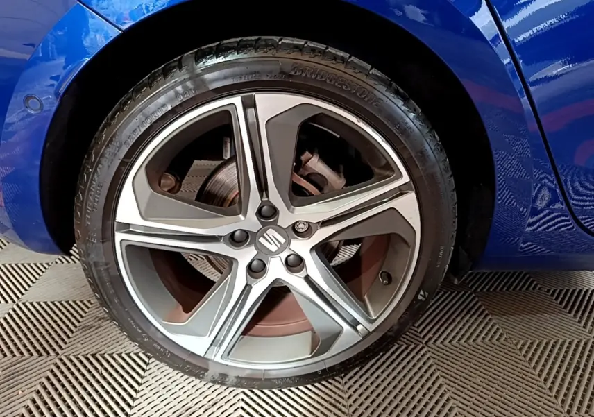 Gros plan sur la roue avant droite d'une SEAT Leon bleu 2021 avec jante alliage cinq branches et logo central.