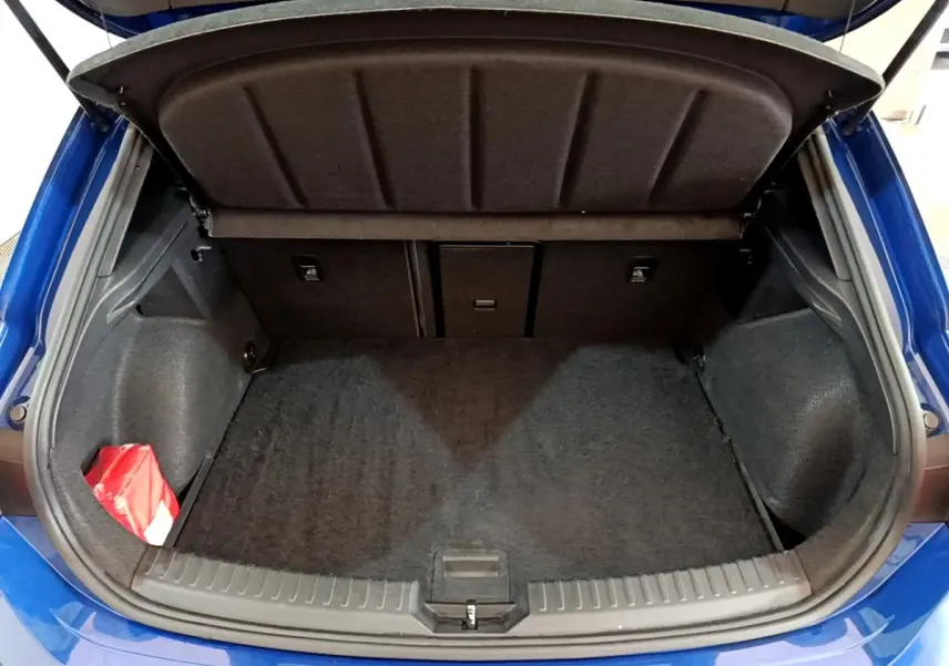 Coffre ouvert d'une SEAT LEON bleu 2021, vue arrière montrant un espace de rangement propre et un kit de secours rouge.