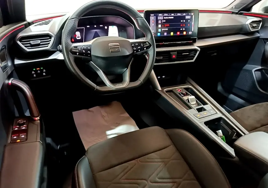 Vue intérieure avant droite du tableau de bord et volant cuir alu du SEAT Leon 1.5 eTSI bleu avec écran tactile et console centrale.