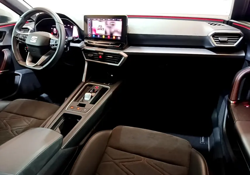 Vue intérieure côté conducteur du tableau de bord et console centrale du SEAT Leon bleu avec écran tactile et volant multifonctions.