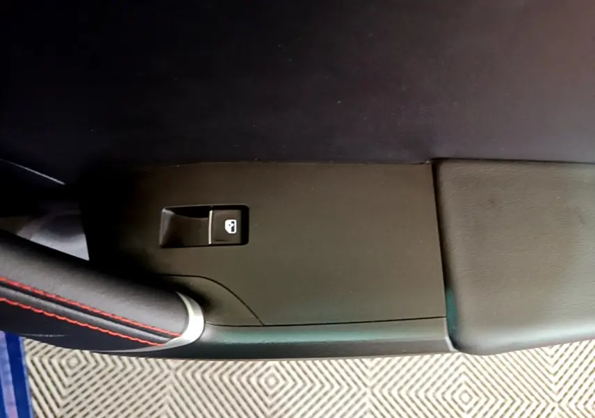 Détail de la poignée de porte intérieure côté gauche avec bouton de verrouillage, sur SEAT Leon bleu 2021.