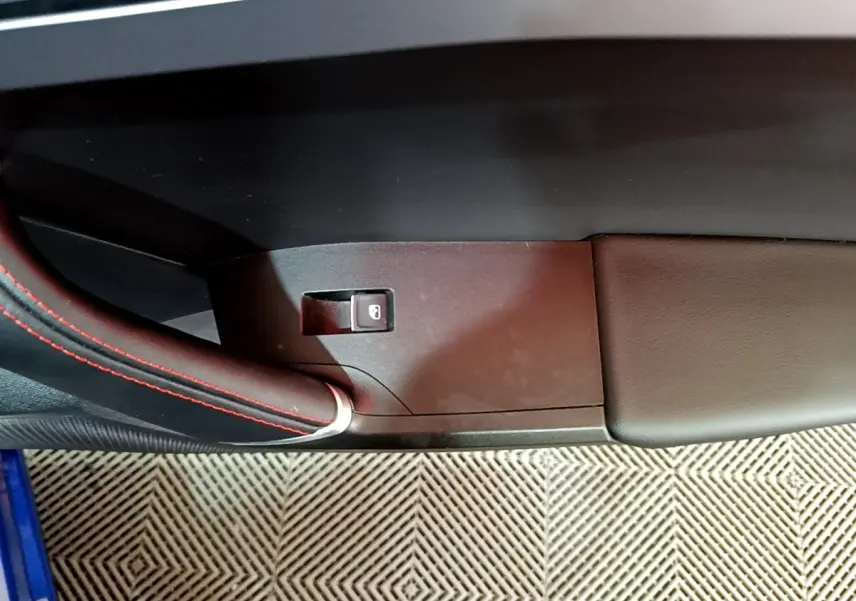 Détail de la poignée intérieure côté gauche avec surpiqûres rouges sur une SEAT Leon bleu 2021.